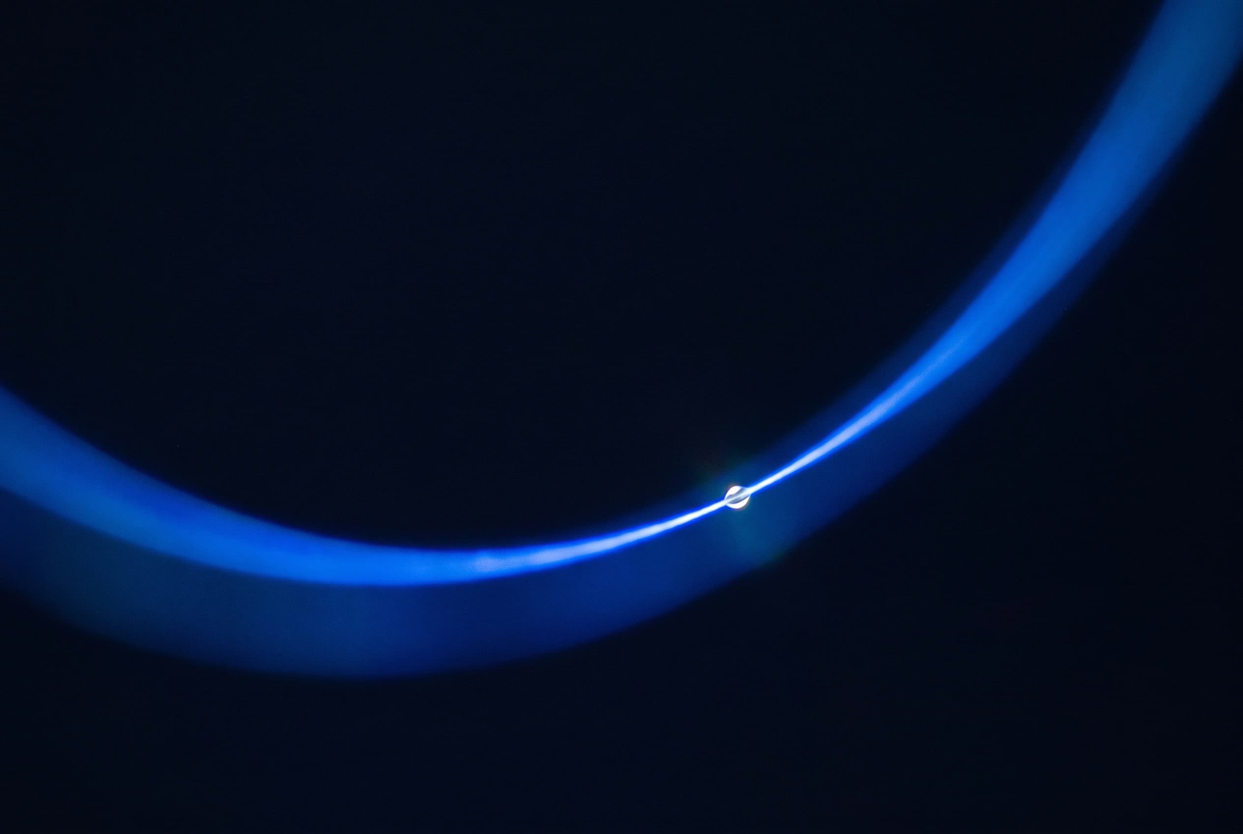 A single thin arc of blue light curving across a dark background