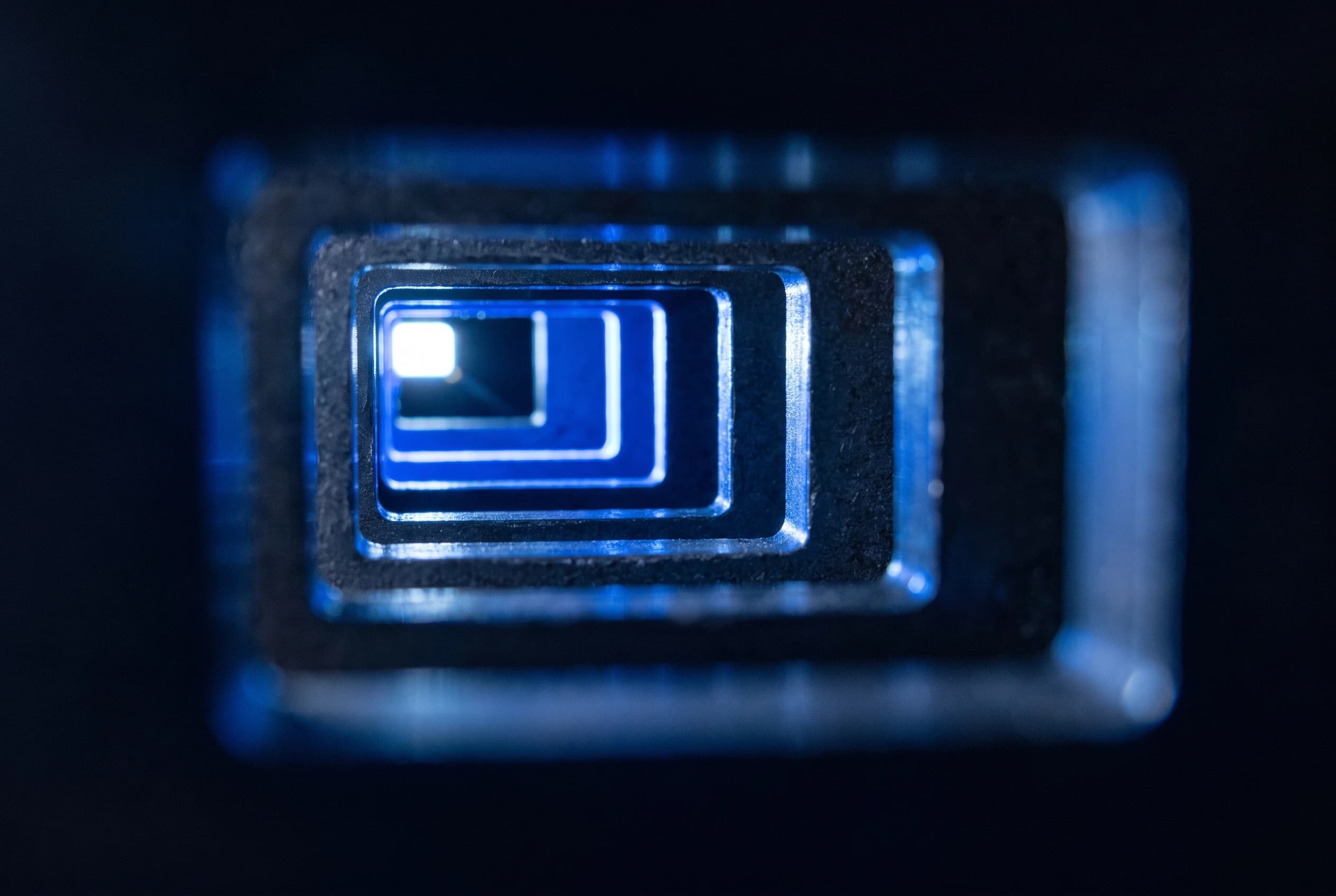Nested machined frames receding toward a point of light, lit in blue