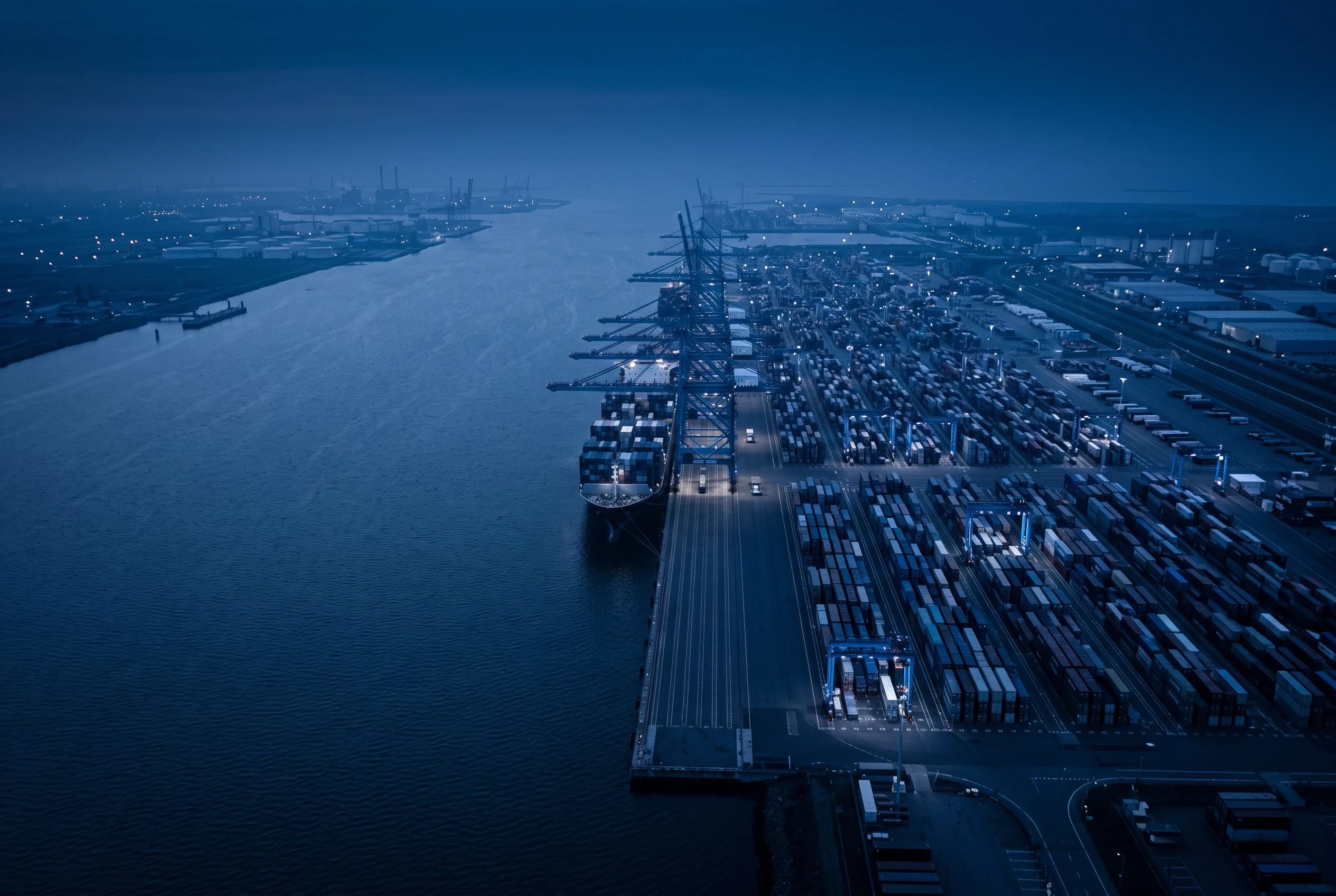 Aerial view of a container port at dusk, ships berthed along the quay