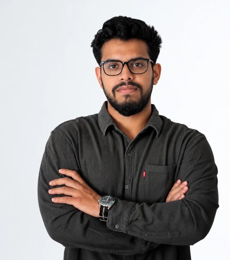 Portrait of Akash Singh, arms crossed, against a light grey wall
