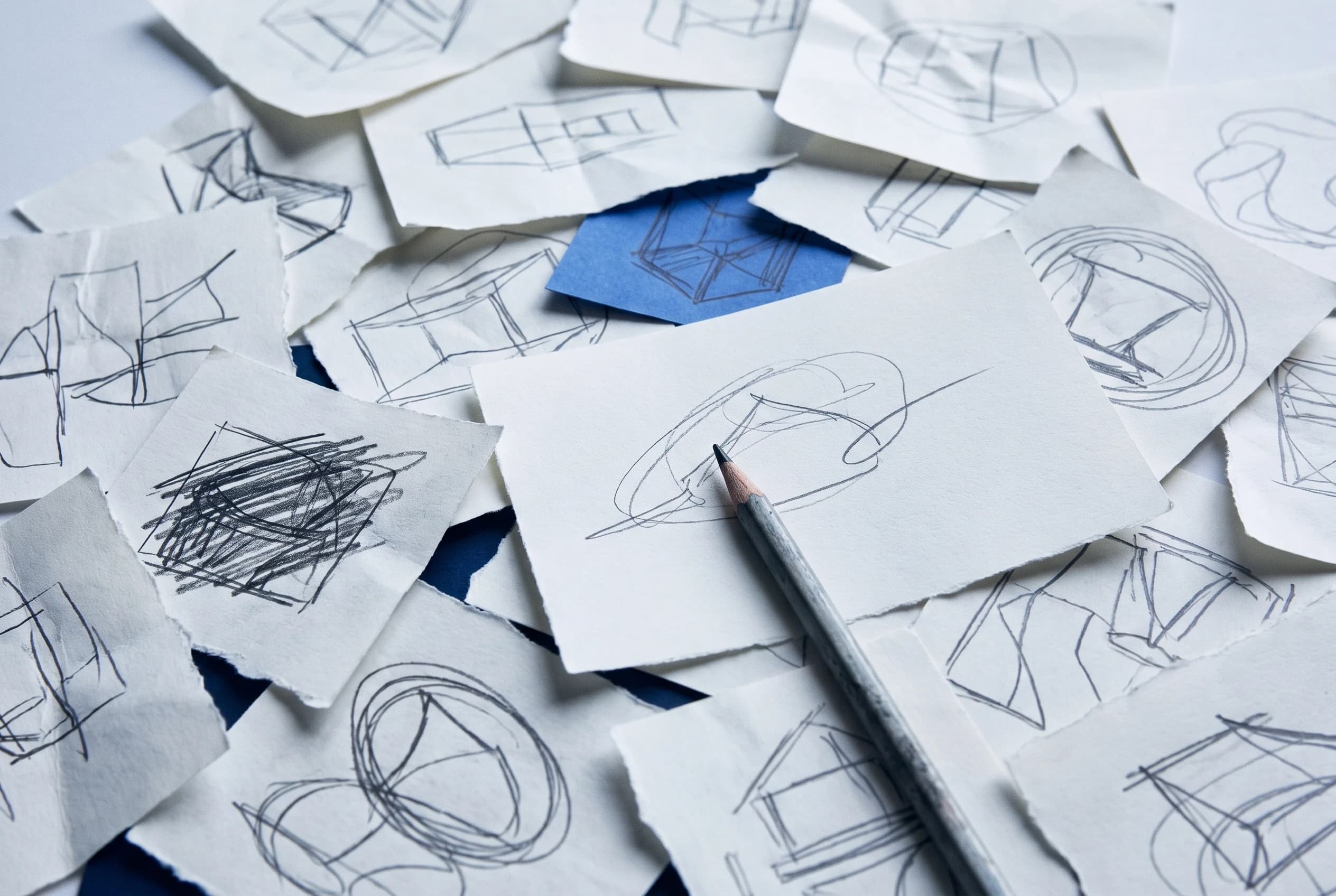 Scattered pencil sketches on torn paper, one sheet in blue