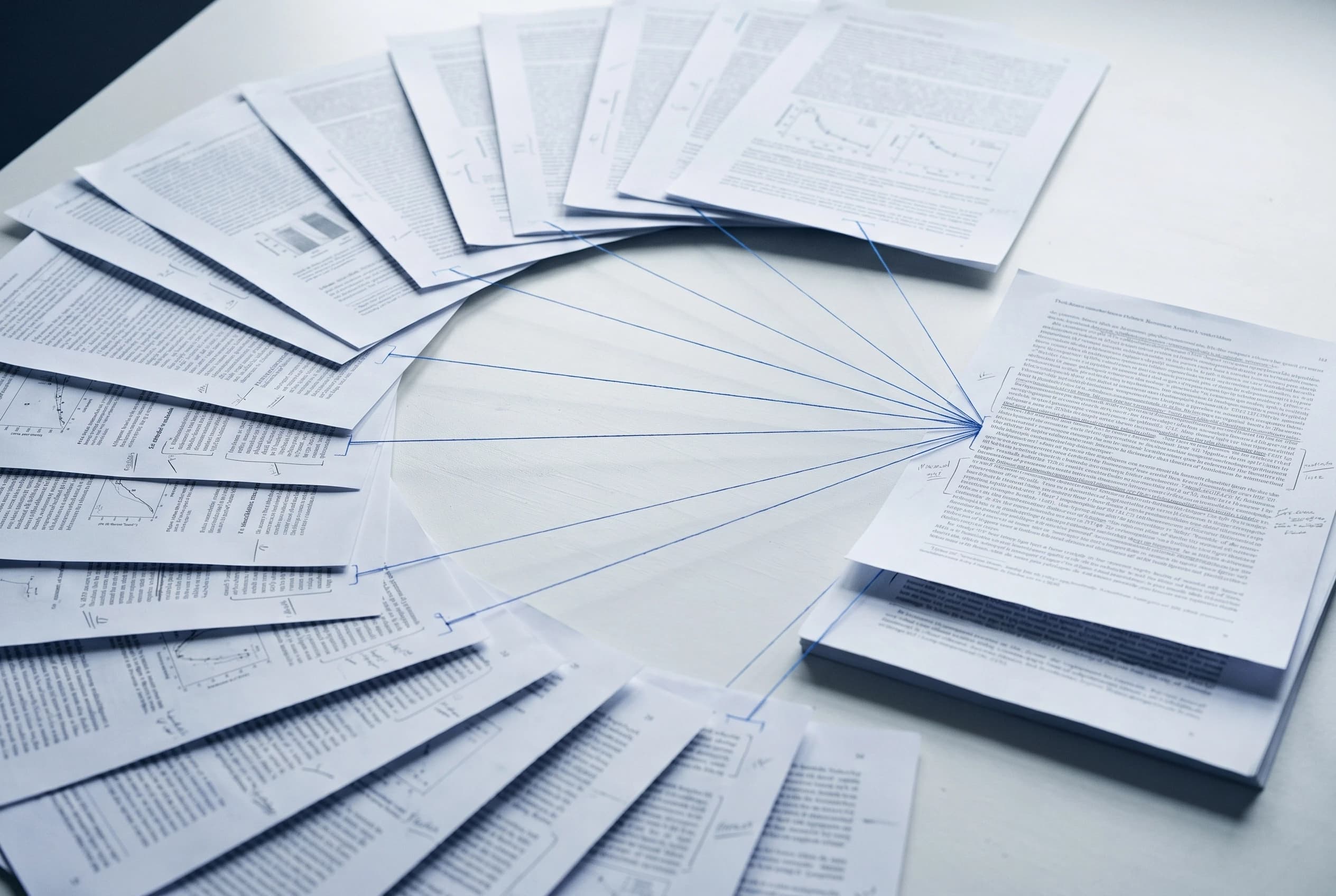Research papers fanned in an arc, blue threads linking them to one document