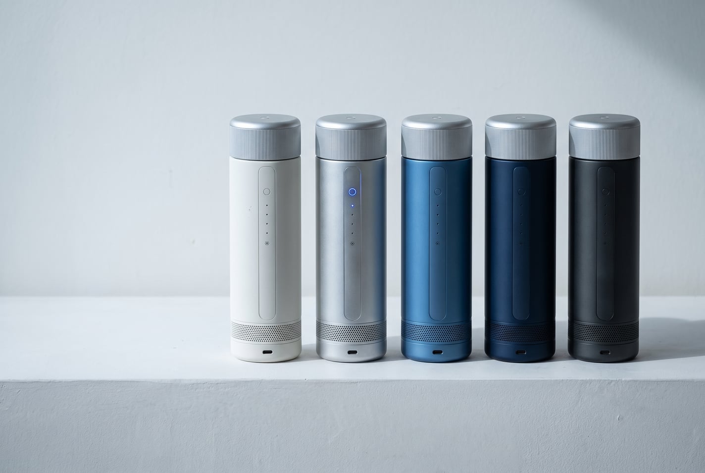 Five CELSIUS ONE units with silver caps on a white ledge, in white, silver, blue, navy and charcoal