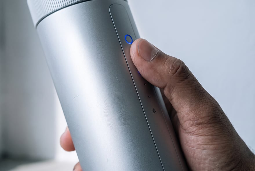 A thumb rests on the lit blue touch ring at the top of the flush aluminium control spine